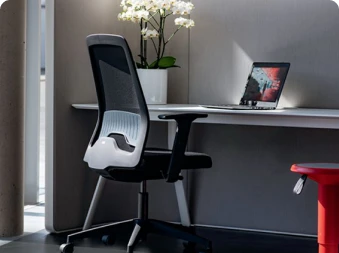 Bilde av en svart kontorstol foran ett skrivebord med en laptop