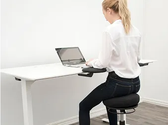 En person som som sitter på en ergonomisk kontorstol og jobber på en laptop