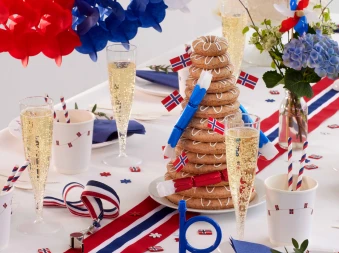 Ett dekket bord med kransekake og masse flagg, glagg løper og flagfarget sugerør