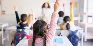 Ett klasserom hvor barn rekker opp hånden