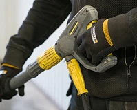 En person som holder en høytrykk spyler med hansker på