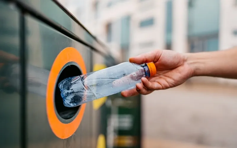 Enm person som kildesorterer en flaske