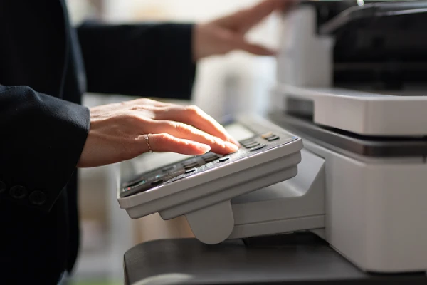 En person som bruker tastene på en stor kopimaskin