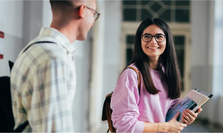 En person som snur seg rundt og ser på en annen med noe bøker i hånden