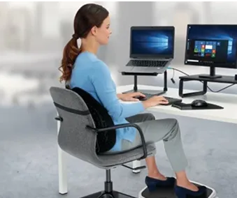 En person som sitter ved et skrivebord med en bærbar Pc og skjerm