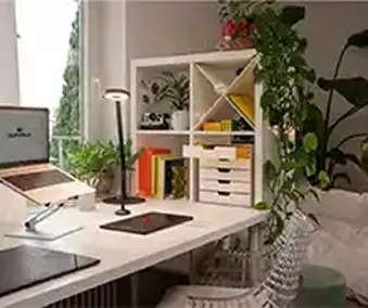 Ett skrivebord med diverse kontorrekvisita og et skuffekabinett