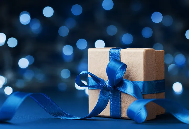 En pakke i gråpapir, med ett blått bånd og sløyfe. Bakgrunnen er som en blå stjernehimmel.