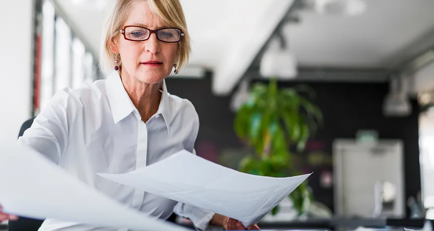 En person som rekker noen papir i rettning kamera