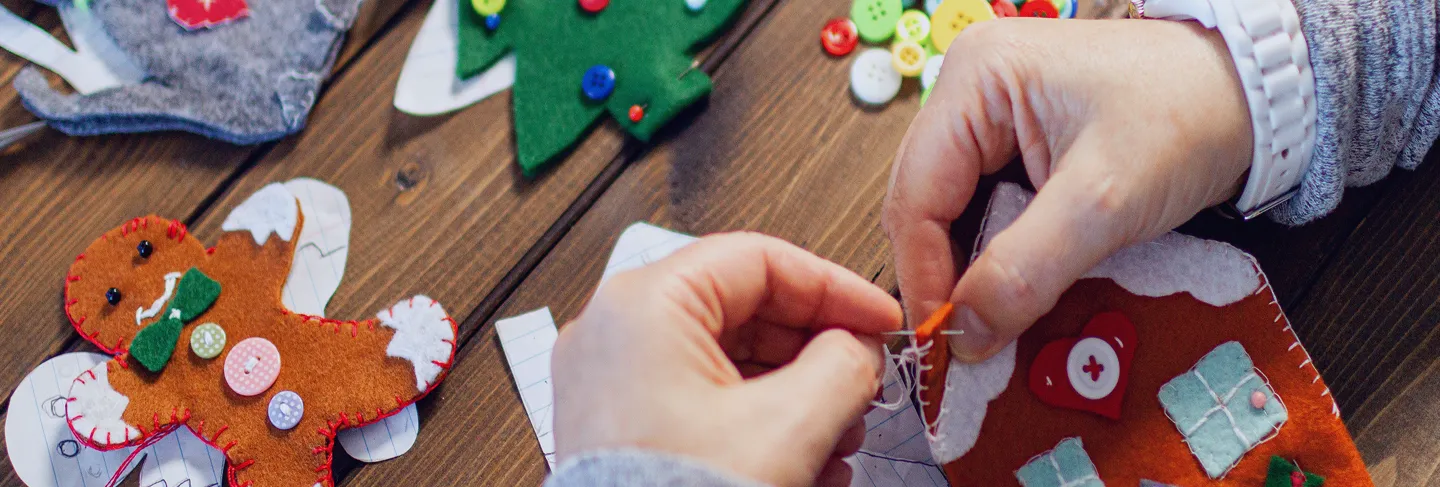 En person som syr juledekorasjo med filt
